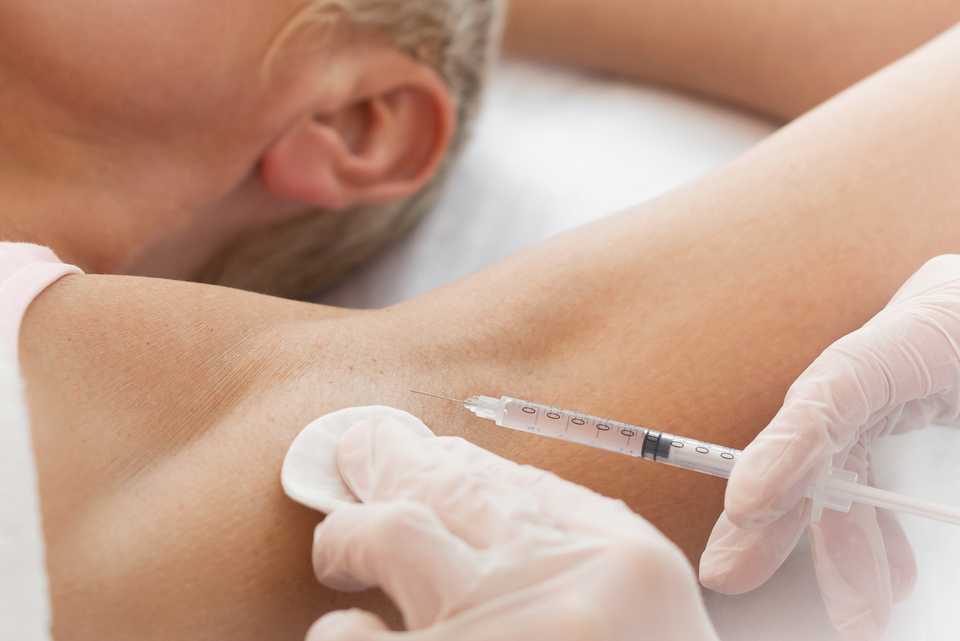 Врач делает укол в область подмышки