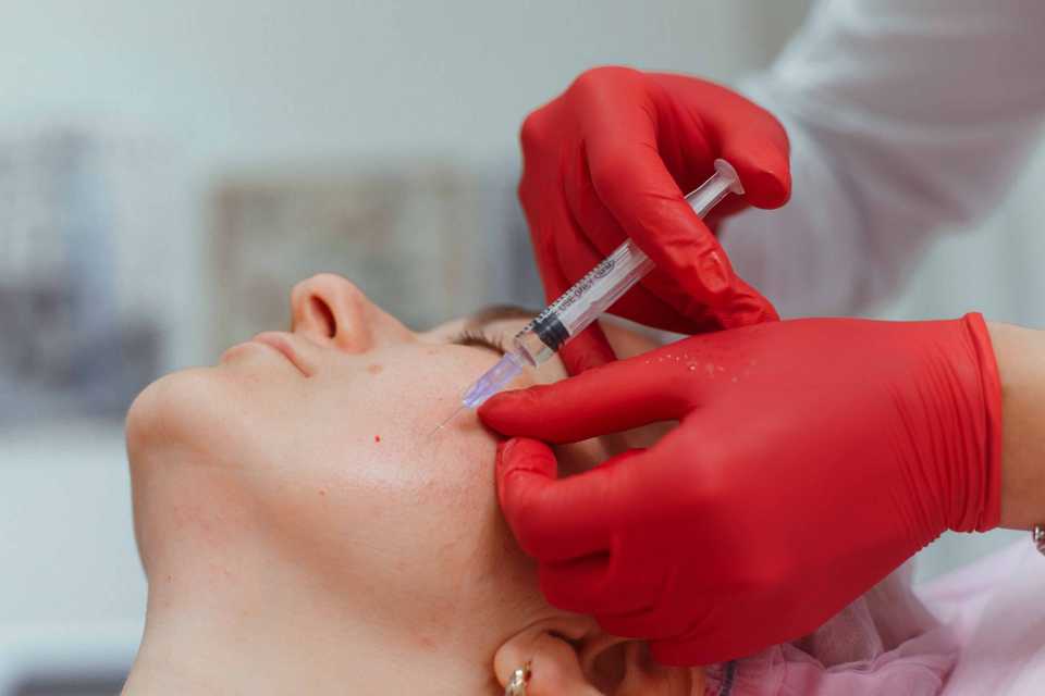 Врач во время проведения мезотерапии вводит препарат в кожу лица