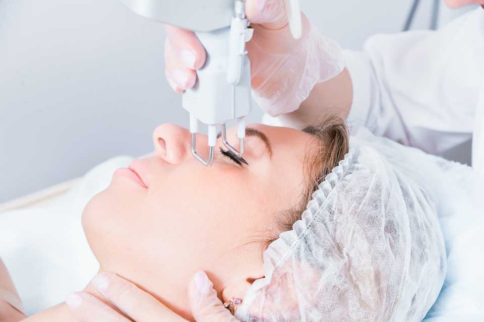 Врач-косметолог проводит фракционное лазерное омоложение