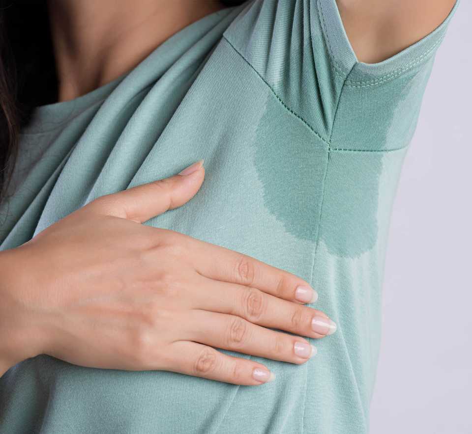 Девушка в мокрой футболке в области подмышки